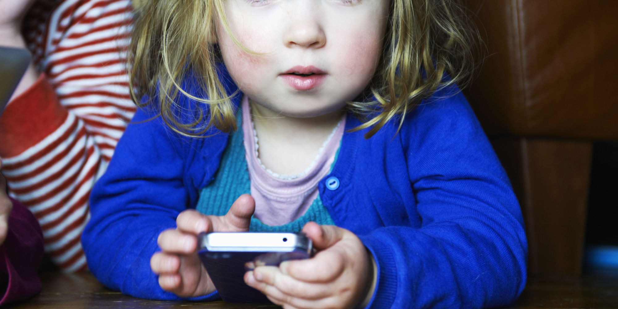 young girl holding mobile phone looking to camera